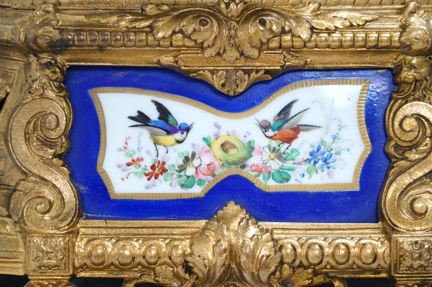 A large gilt metal figural mantel clock with floral porcelain dial and panels, under a glass dome, 52cm high (including stand). Condition - fair, not tested as working